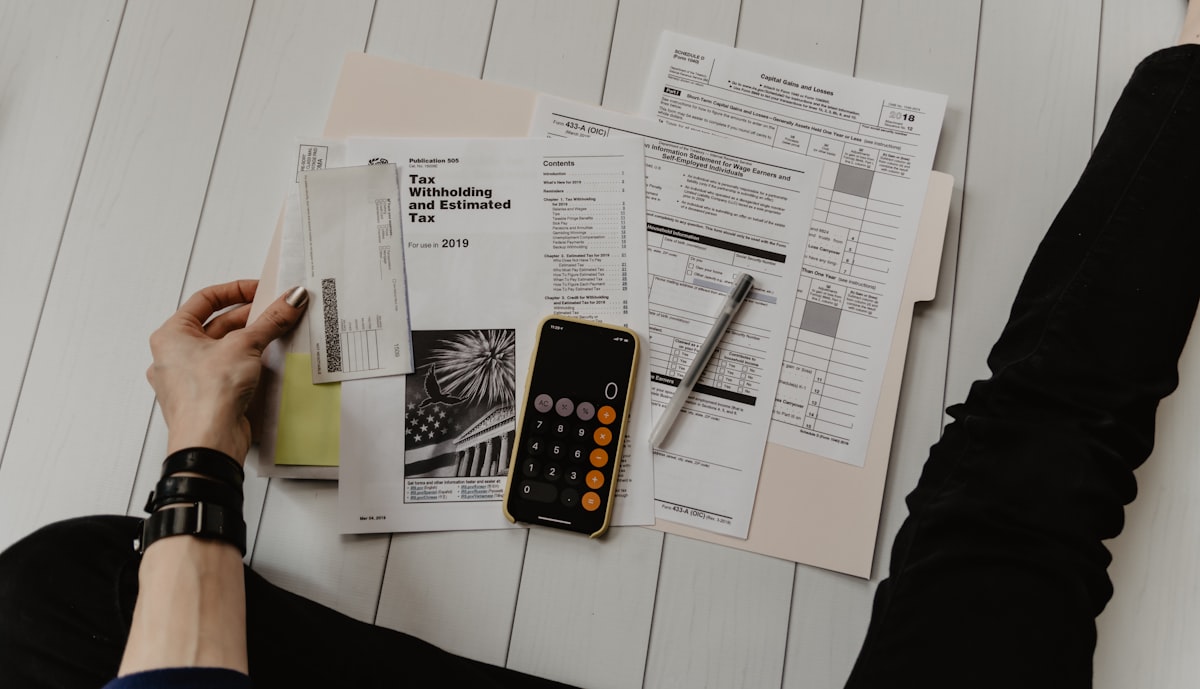 Printed forms, a pen and a calculator arranged on a desk.